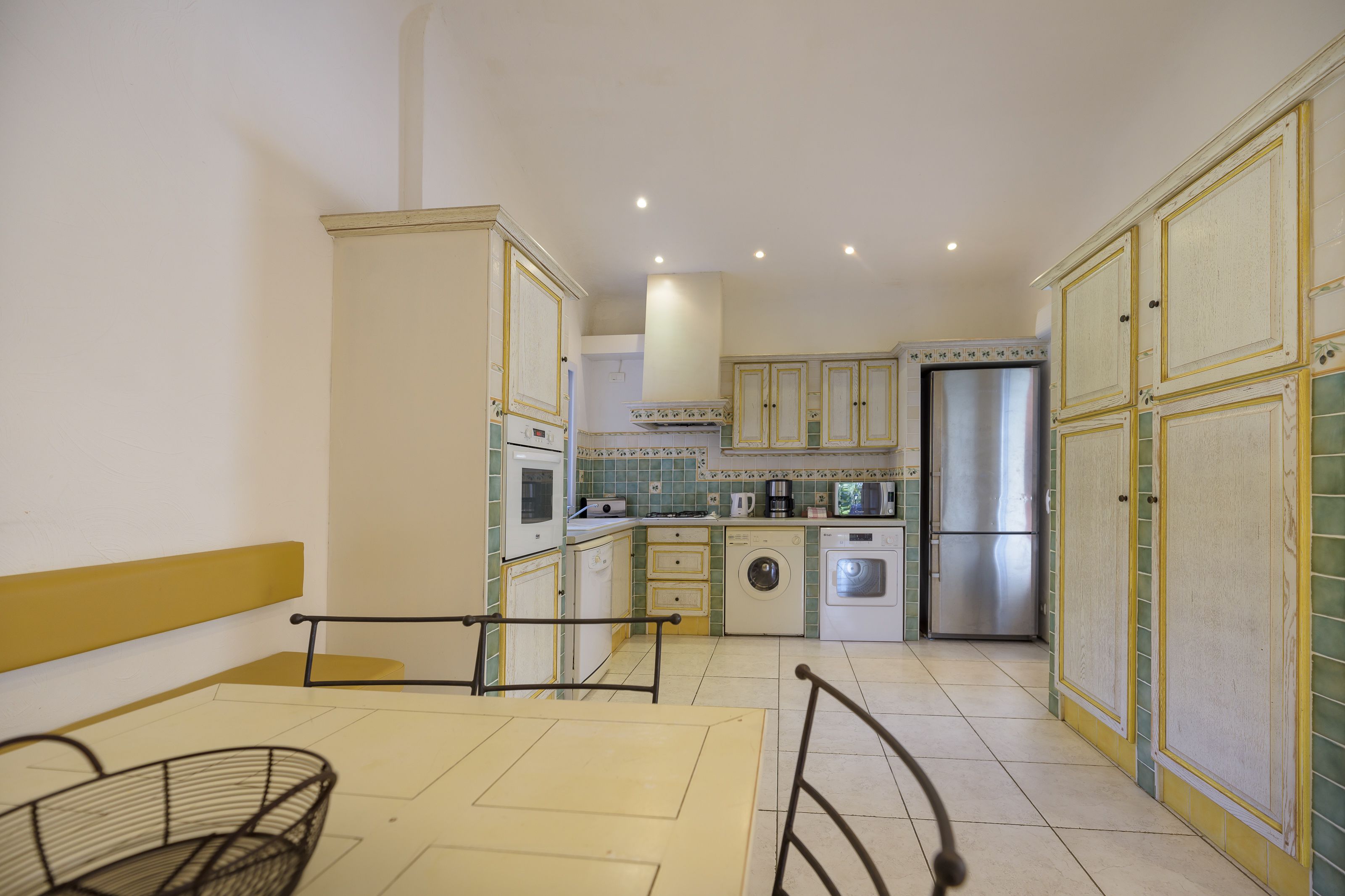 A compact kitchen with white cabinets, a washing machine, and a refrigerator.