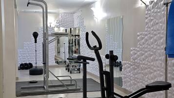 Ein Fitnessraum mit Trainingsgeräten, einem Spiegel und einer Wand mit Musterung.