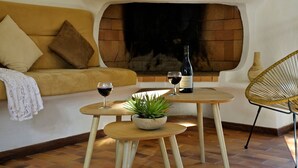 A cozy living area with a sofa, a small round table with a plant, two wine glasses, and a bottle of wine. - Hotel Residence U Paesolu (Zonza)