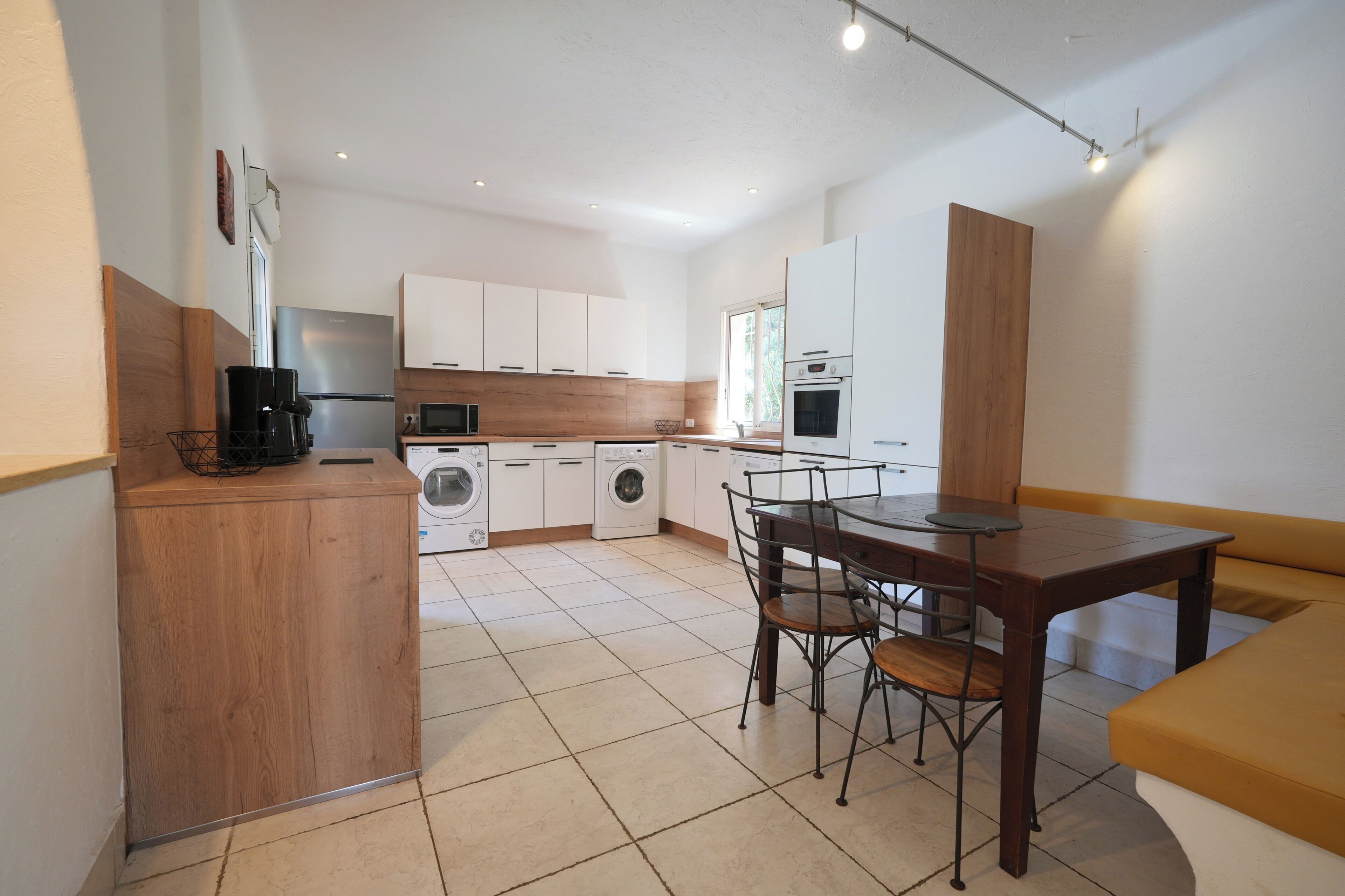 A modern kitchen with a dining area, built-in appliances, and a wooden accent wall.