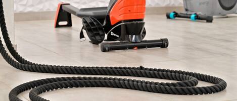 A stationary exercise bike with a coiled resistance band on the floor.