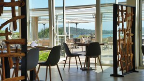 An indoor dining area with large windows, wooden furniture, and a view of the sea. - Hotel Residence U Paesolu (Zonza)