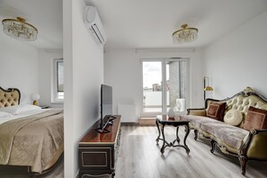 A modern bedroom with a bed, a dresser, a TV, a sofa, and a chandelier. - Vision Aparthotel (Budapest)