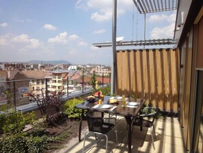 A balcony with a table set for two, overlooking a cityscape. - Vision Aparthotel (Budapest)