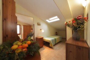 Ein Schlafzimmer mit Bett, Nachttisch, Kommode, Fenster und Oberlicht.