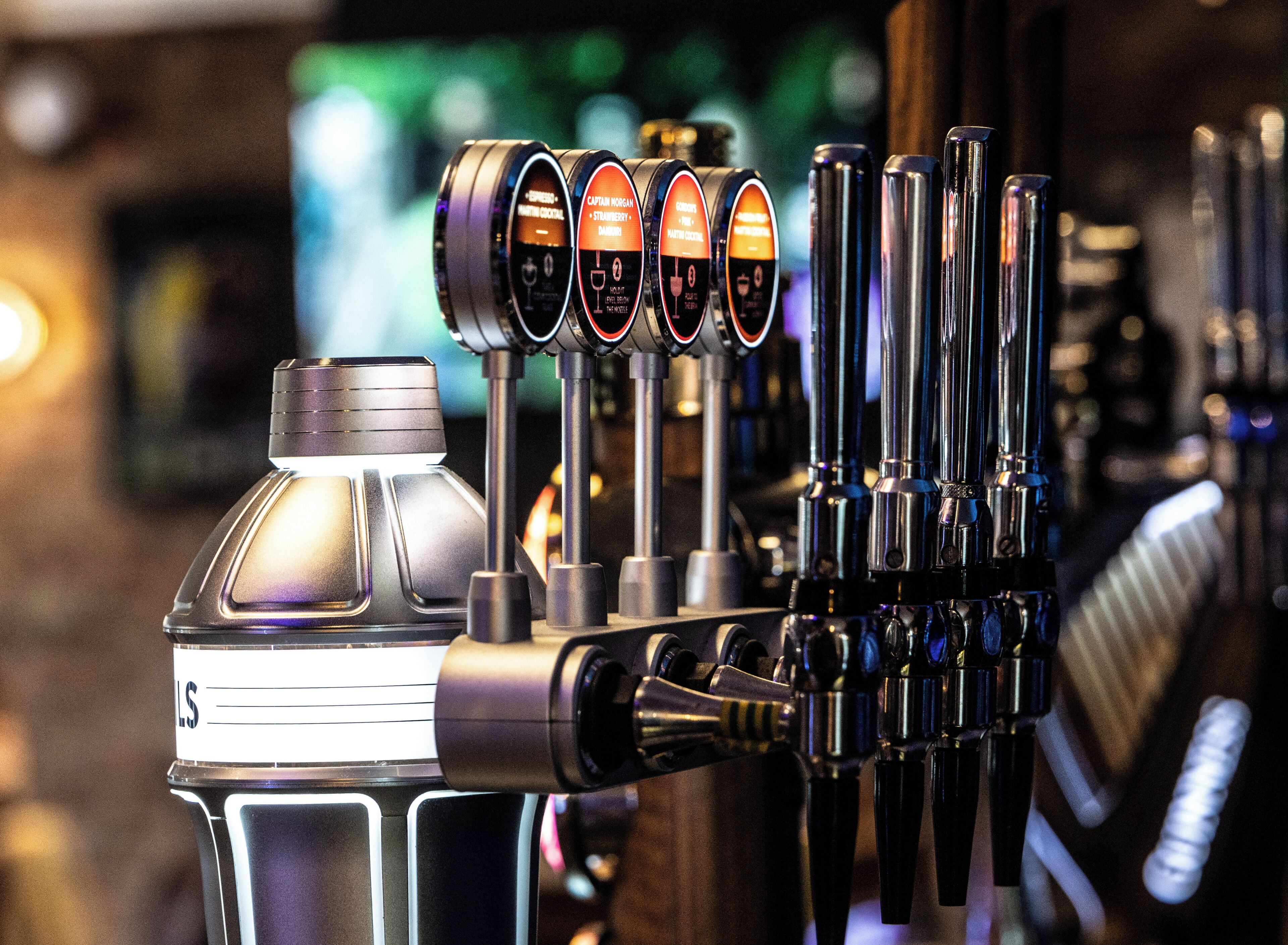 Un bar con varias llaves de cerveza, una botella de agua y un fondo desenfocado.