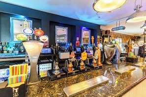 A bar area with multiple beer taps, a large beer mug, and various bottles.