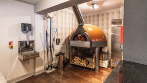 A kitchen with a wood-fired oven, a sink, and a mop. - The Littleover Lodge Hotel (Derby)