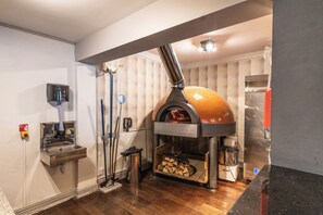 Une cuisine équipée d’un four à bois, d’un évier et d’une serpillière.