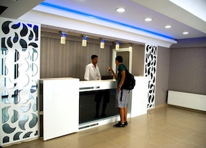 A reception area with a modern design, including a reception desk, a large mirror, and decorative wall panels. - Blue Marine Hotel (Istanbul)