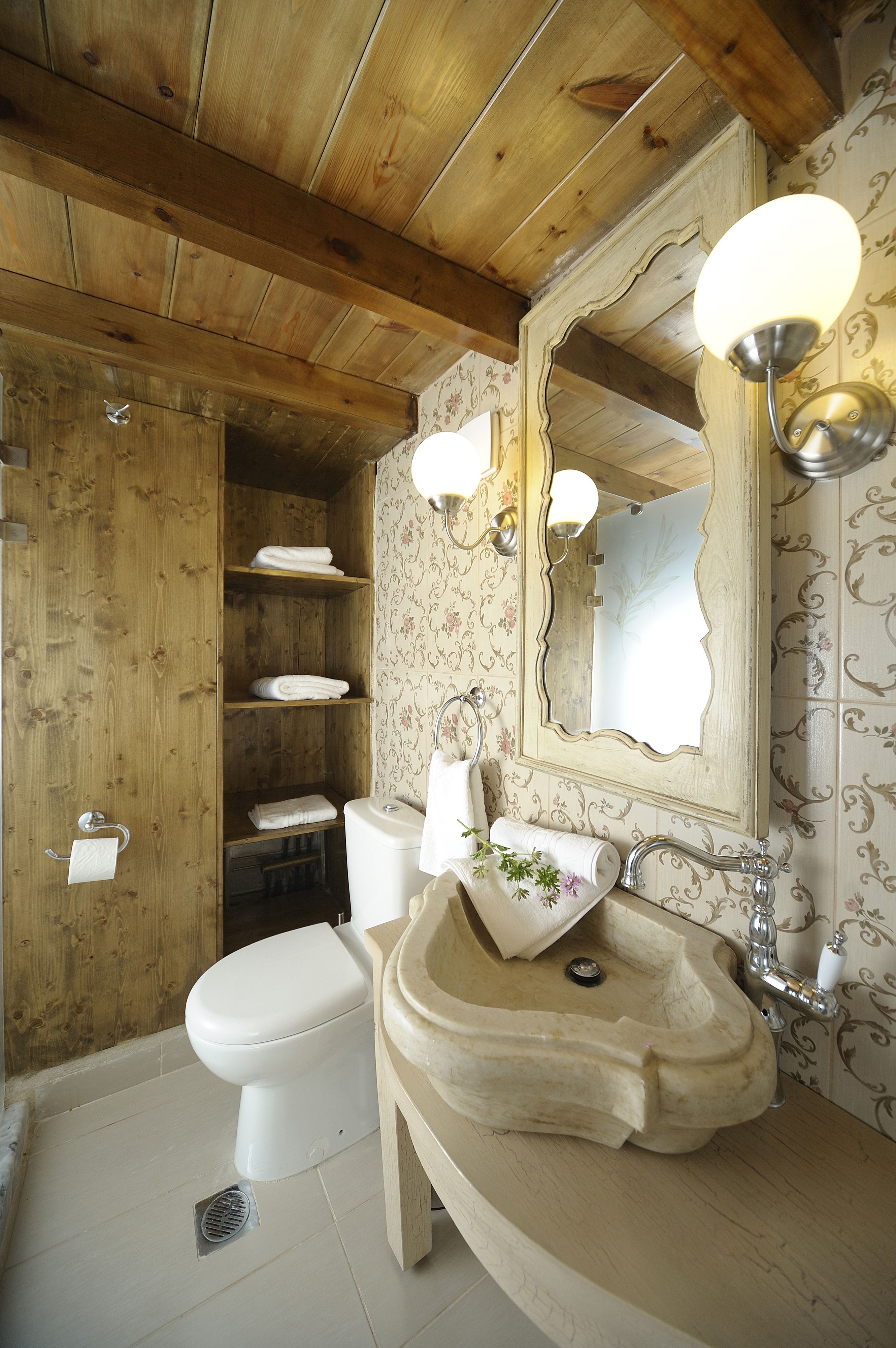 Un bagno in legno con servizi igienici, lavabo e scaffali.