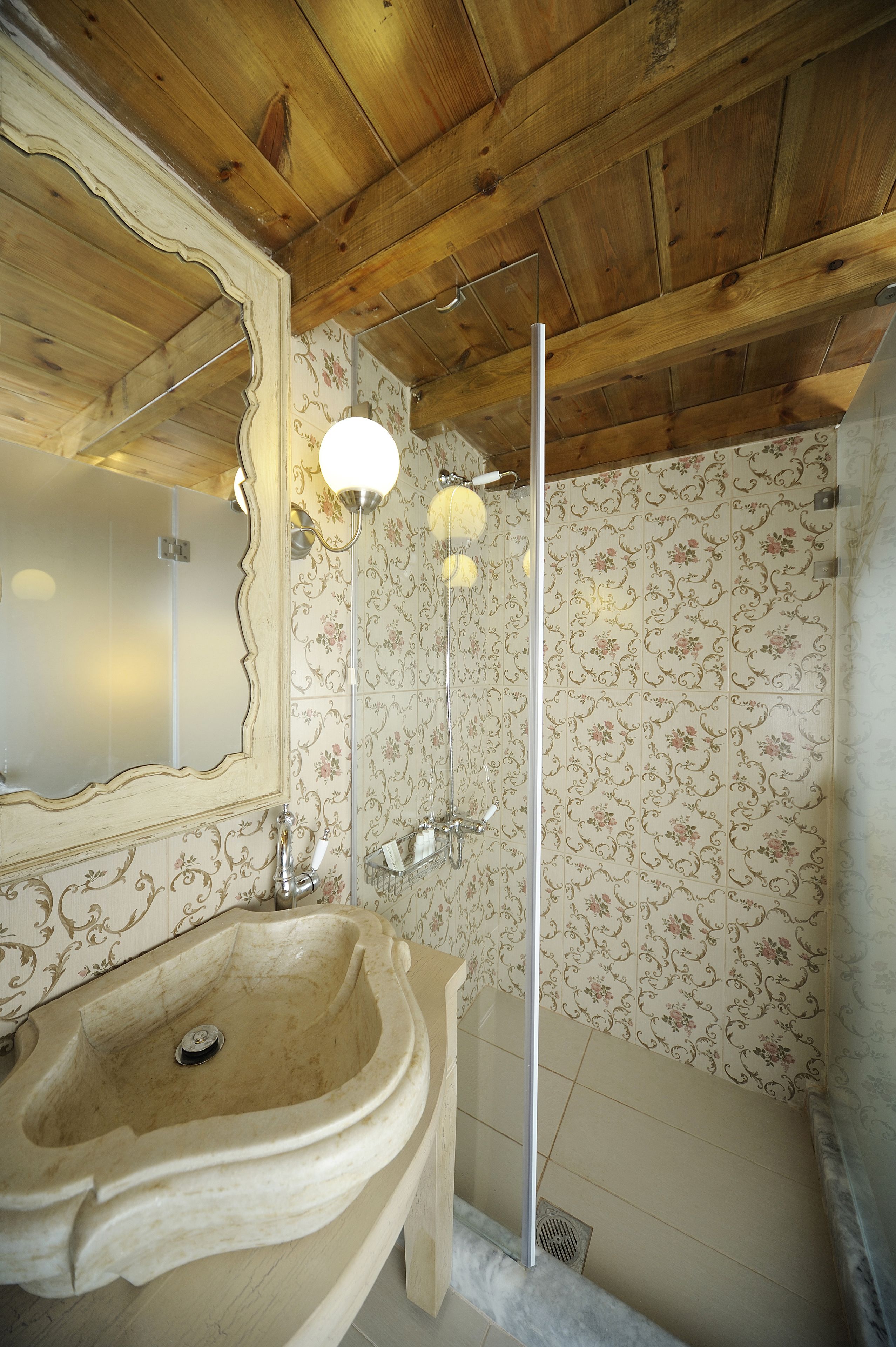 A bathroom with a large sink, a mirror, and a shower with a wooden ceiling.
