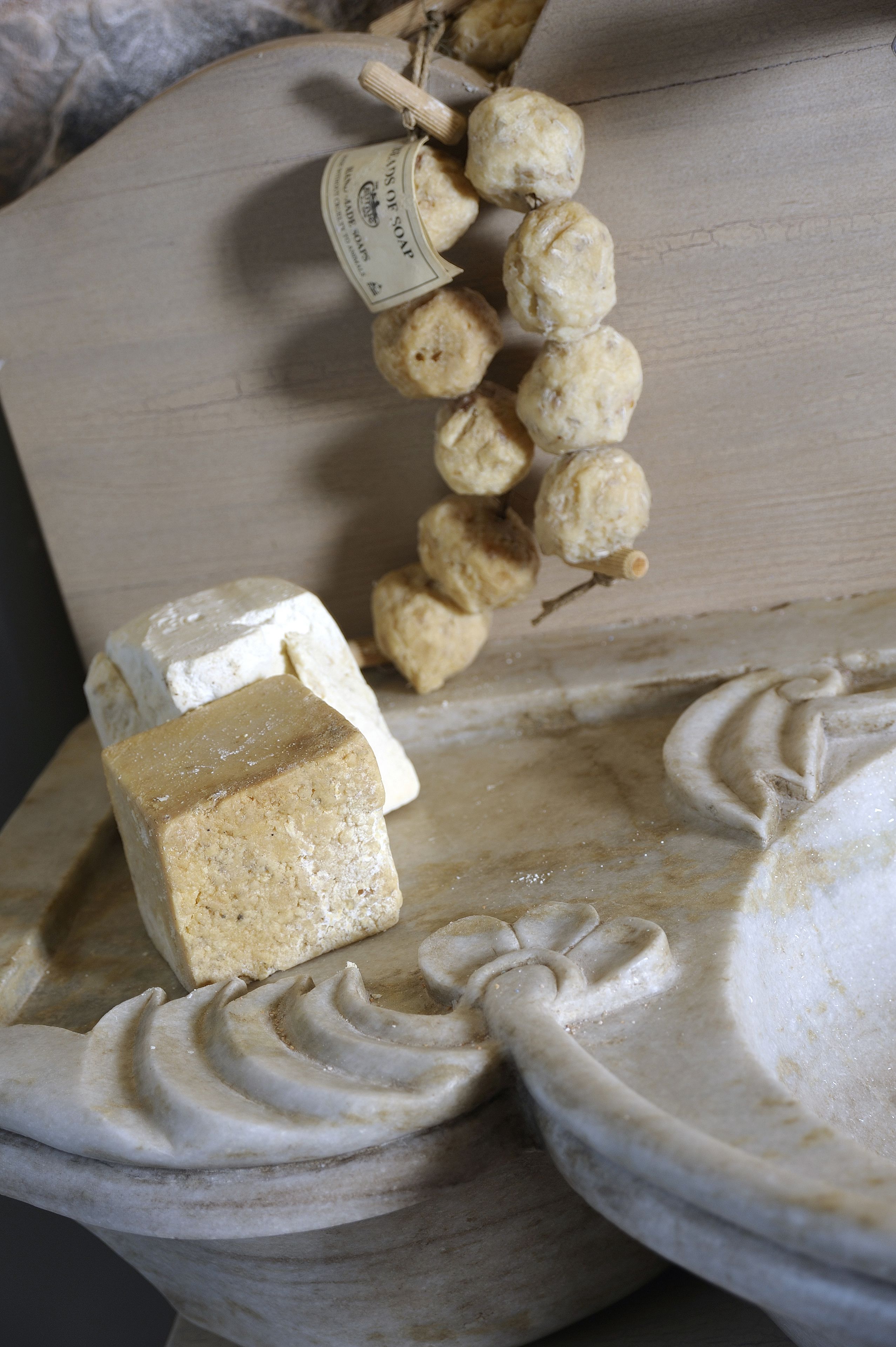 A marble surface with a soap bar and a hanging soap dispenser.