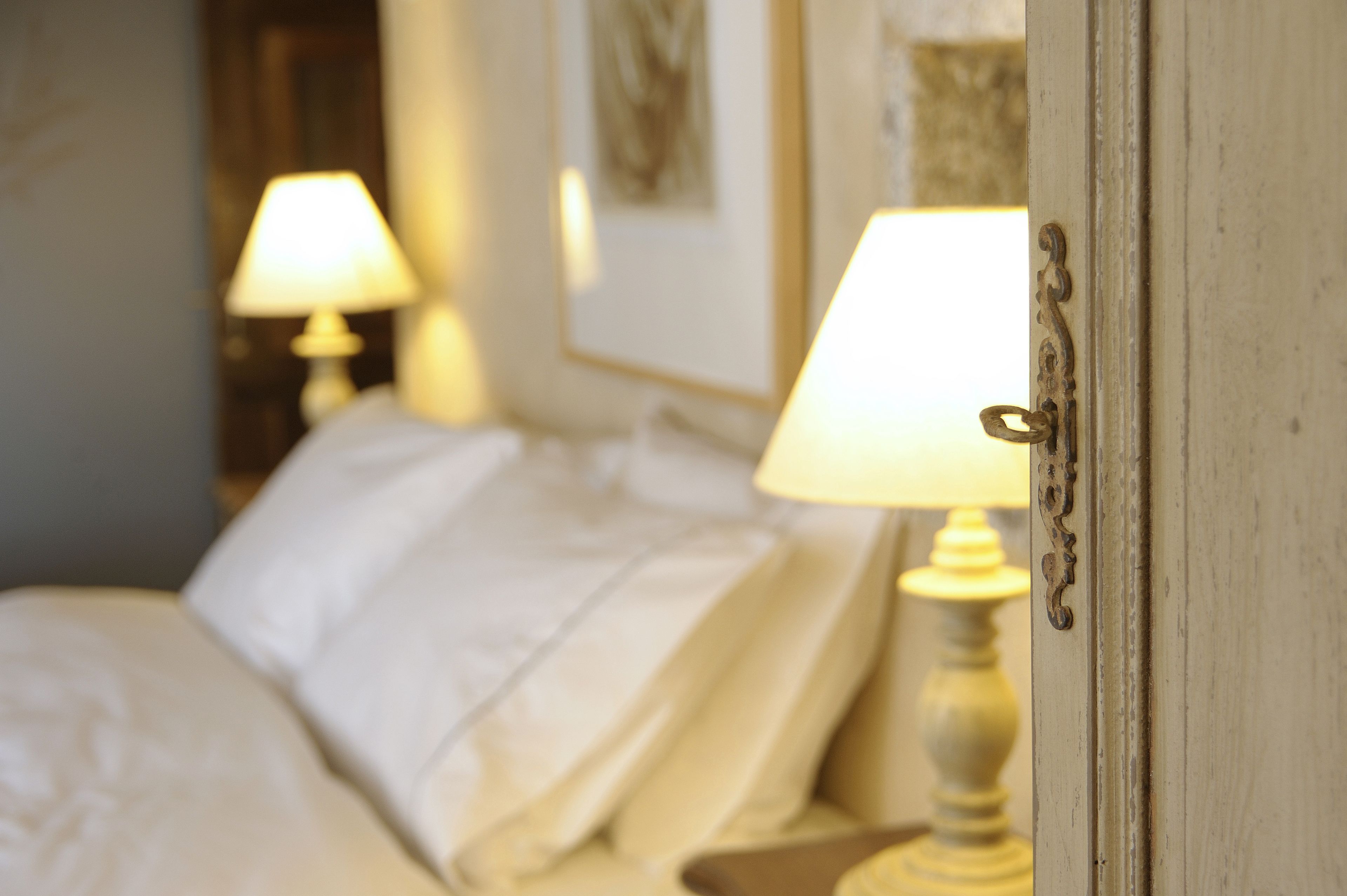A hotel room with a bed, a nightstand, and a lamp.