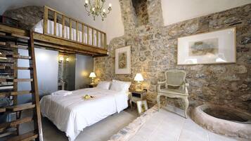A bedroom with a bunk bed, stone walls, a fireplace, and a wooden ladder.