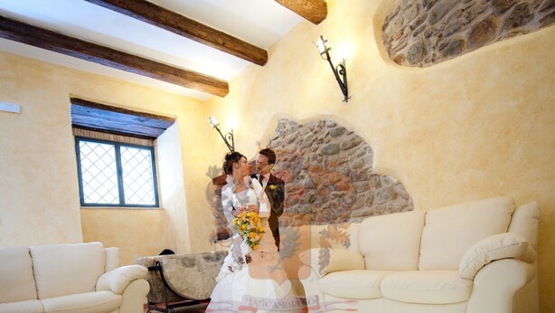 A room with a glass coffee table reflecting a stone wall and a window. There are two white sofas and a stone wall with a stone arch. - Palazzo Mascambruno (Cariati)