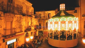 A traditional building with a central courtyard, featuring a brightly lit, ornate structure with people gathered around. - Palazzo Mascambruno (Cariati)
