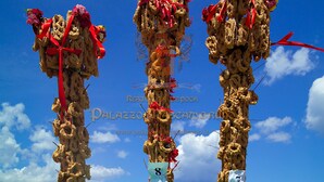 Three tall structures adorned with red ribbons and flowers against a clear blue sky. - Palazzo Mascambruno (Cariati)