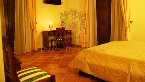 A hotel room with a bed, a desk with a lamp, a chair, and curtains. - Palazzo Mascambruno (Cariati)
