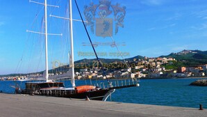 A sailboat docked at a marina with a cityscape in the background. - Palazzo Mascambruno (Cariati)