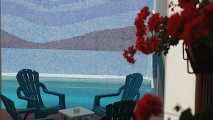 Zona de piscina con dos sillas Adirondack azules y una mesita.