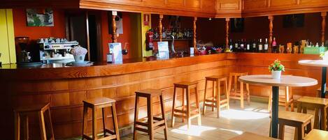 Un espace bar avec des comptoirs en bois, des tabourets et un appareil à café.