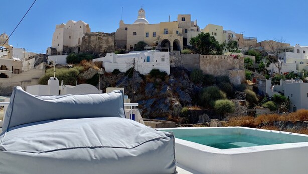 Un edificio blanco con piscina y un almohadón grande en una terraza.