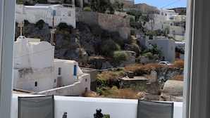 Un balcón con dos sillas y una mesa, con vistas a una colina con edificios blancos y una iglesia.
