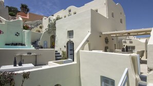 Un edificio encalado con una escalera que lleva a una puerta, rodeado por un cielo azul claro.