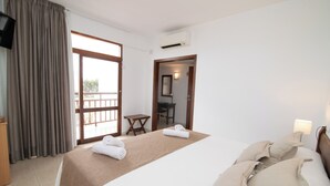 A hotel room with a bed, a desk, a chair, and a view through a large window. - Hotel Galera (Sant Antoni de Portmany)
