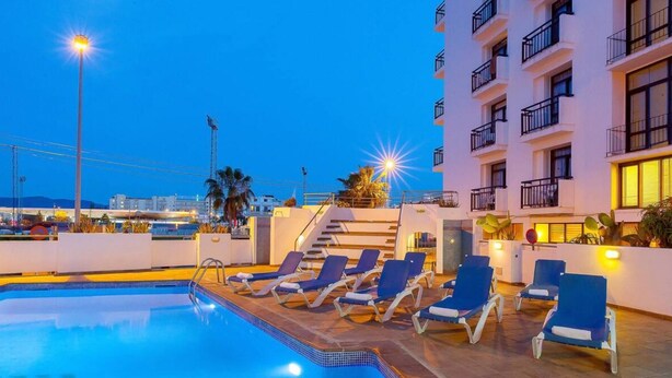 A swimming pool with lounge chairs and a staircase leading to an upper level. - Hotel Galera (Sant Antoni de Portmany)