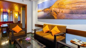 A hotel lobby with a large rock painting, comfortable seating, and a glass coffee table. - Hotel Galera (Sant Antoni de Portmany)