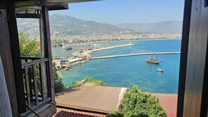 A coastal cityscape with a marina, boats, and a clear view of the city and mountains in the background. - Harmony Boutique Hotel (Alanya)