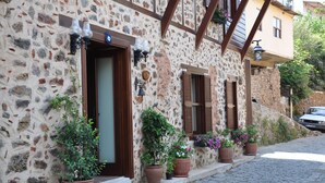 A stone building with wooden shutters, potted plants, and a cobblestone street. - Harmony Boutique Hotel (Alanya)