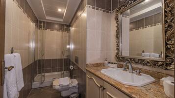 A bathroom with a shower, toilet, sink, and a large mirror.