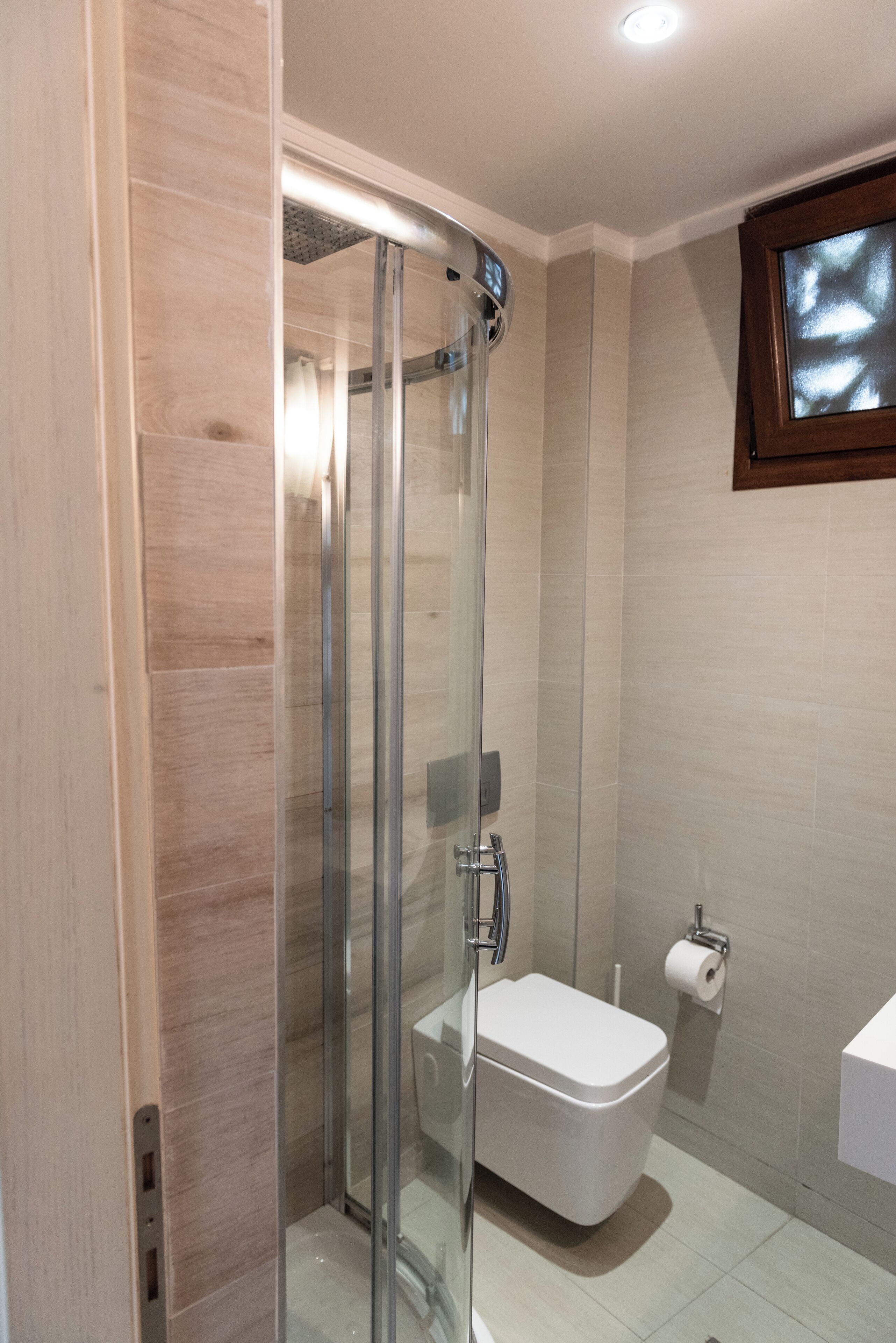 A modern bathroom with a glass-enclosed shower, a toilet, and a sink.
