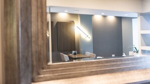 A modern conference room with a wooden table, white chairs, and a large mirror. - Stamos Hotel (Kassandra)