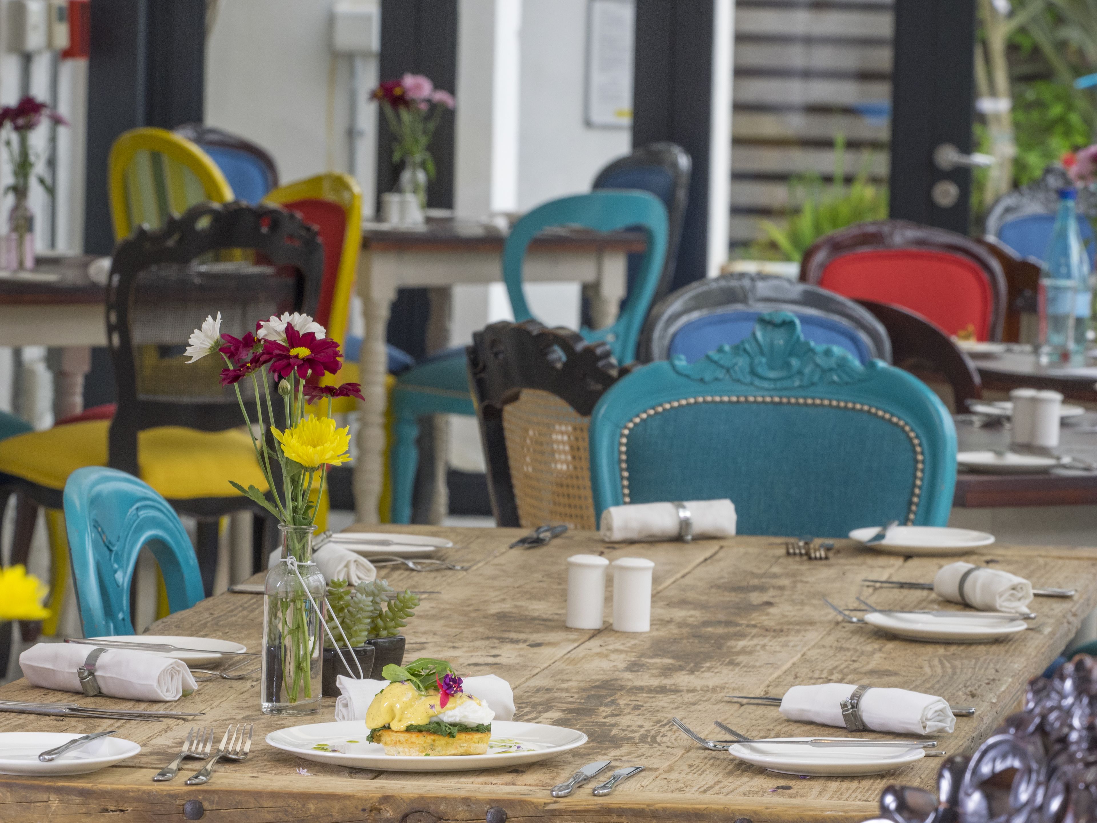 A dining table set with plates, cutlery, and a centerpiece of flowers.