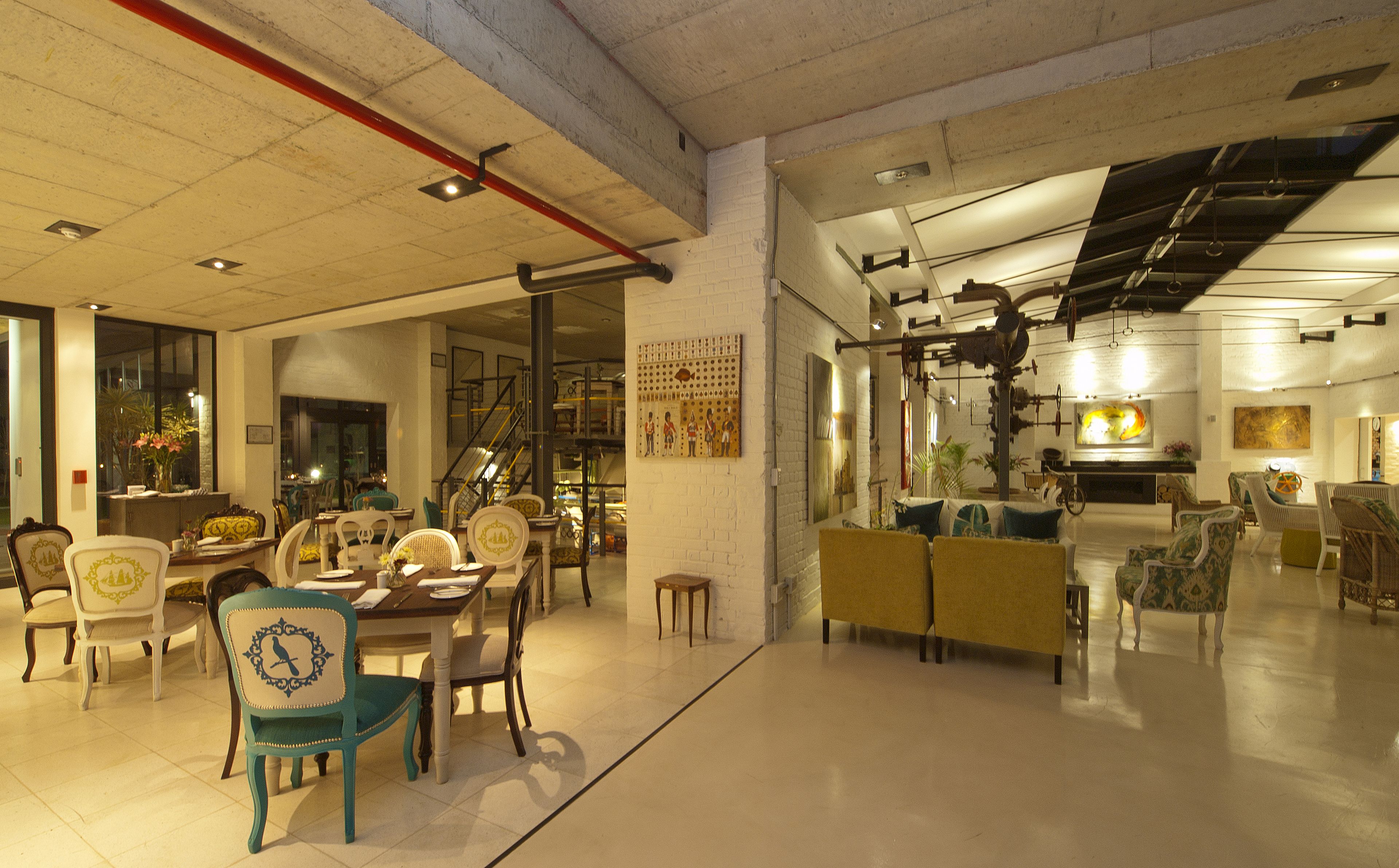 A spacious hotel lobby with a high ceiling, a staircase, and a variety of seating arrangements including chairs and sofas.