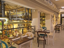 A restaurant with a high ceiling, exposed ductwork, and a dining area with tables set for two.