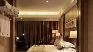 Habitación de hotel con un espejo grande, una cama con almohadas, un escritorio y una bañera llena de pétalos de rosa.