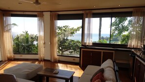 A spacious living area with a sofa, a coffee table, and a view of the ocean through large windows. - Argonauta Boracay Boutique Hotel with Apartments and Villas (Boracay Island)