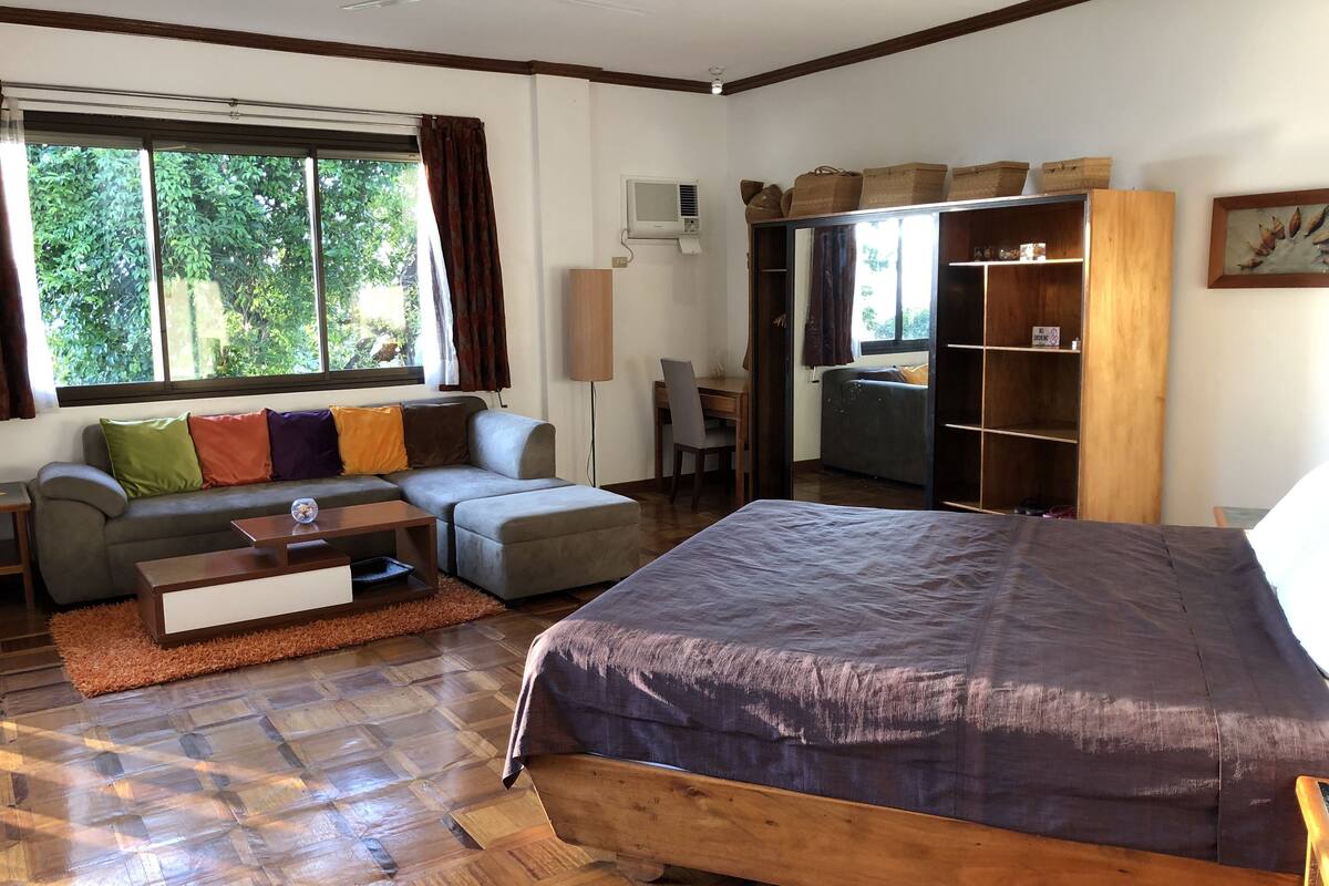 Et moderne soveværelse med en stor seng, en sofa, et skrivebord og et klædeskab.