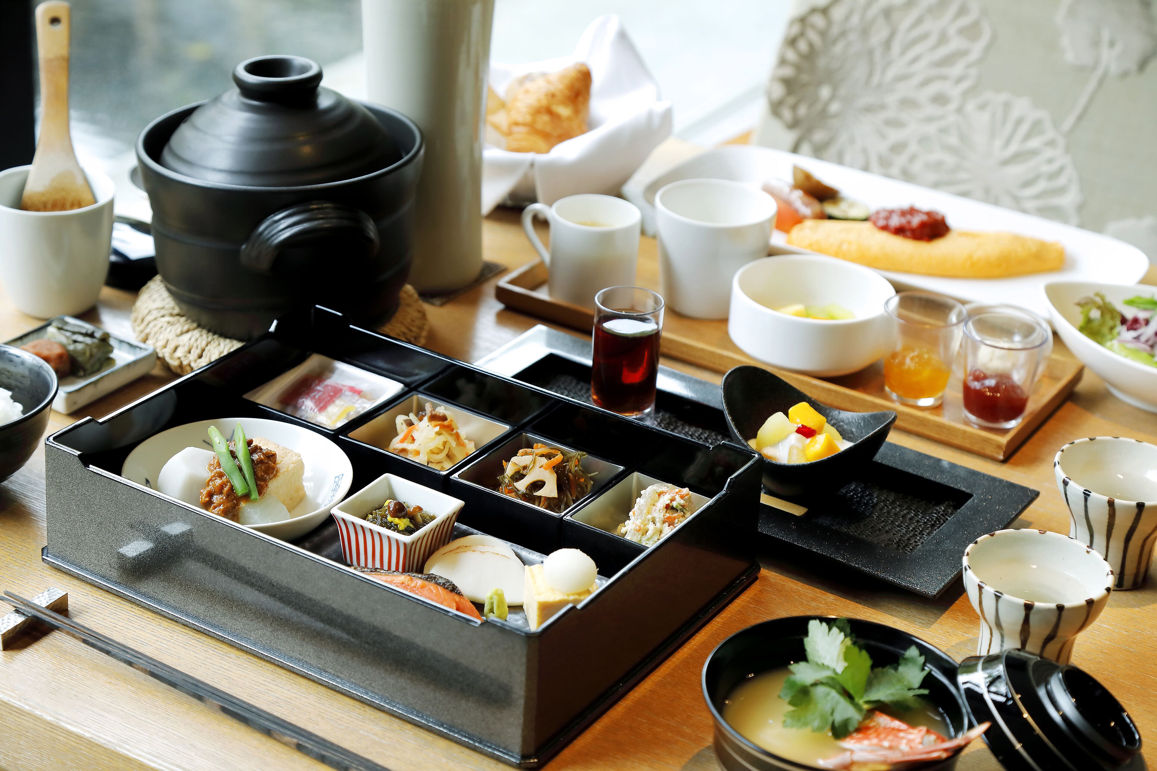 A traditional Japanese meal setup with various dishes and utensils on a wooden table.