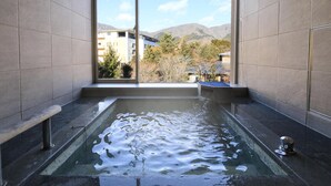A modern bathroom with a large window, a bathtub, and a view of buildings and mountains. - Hakone Hisui (Hakone)