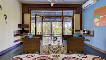 A room with two wicker sofas, a small table, and a bed with a patterned bedspread.