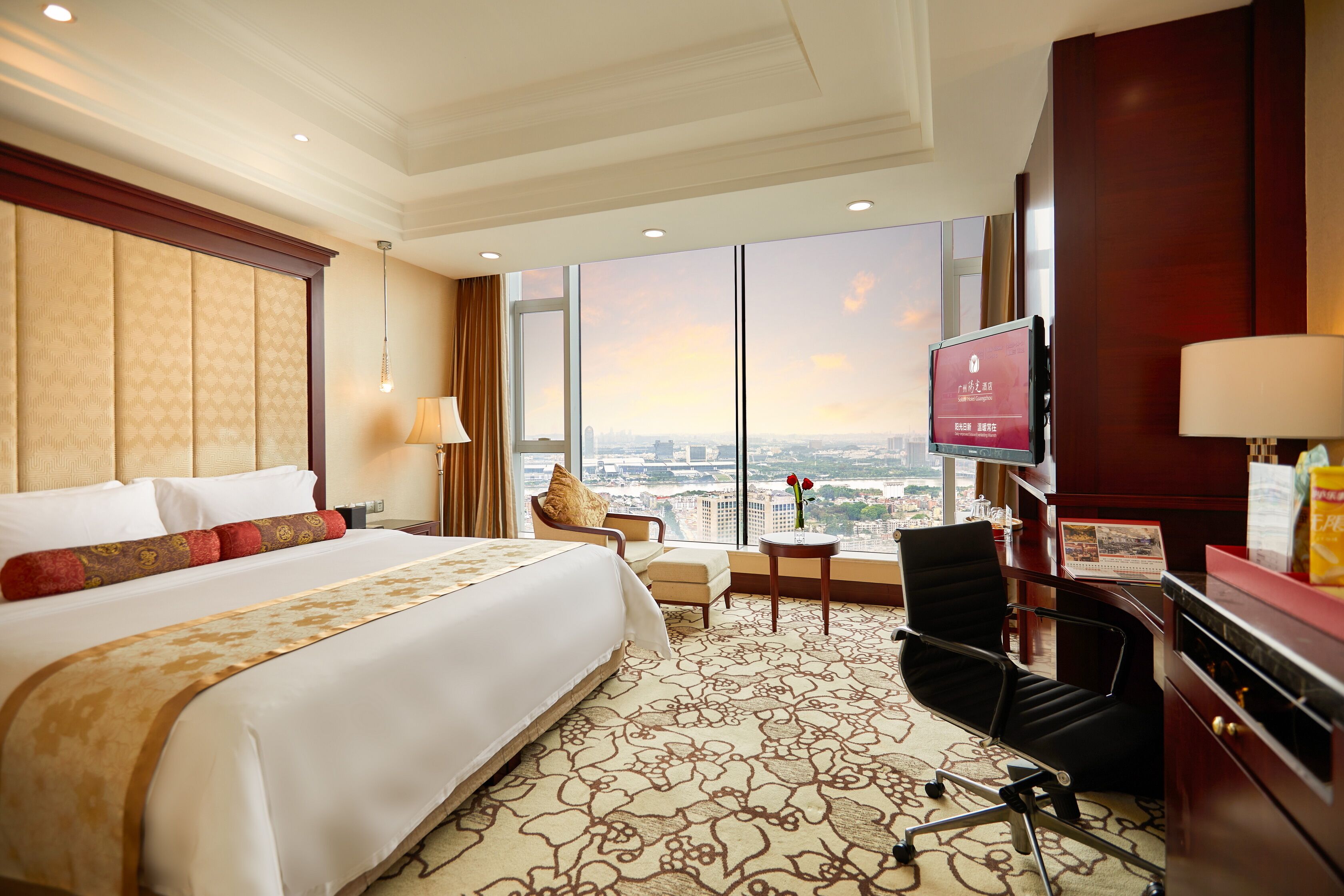 Une chambre d’hôtel avec un grand lit, un bureau avec une chaise, une télévision et une vue sur la ville.