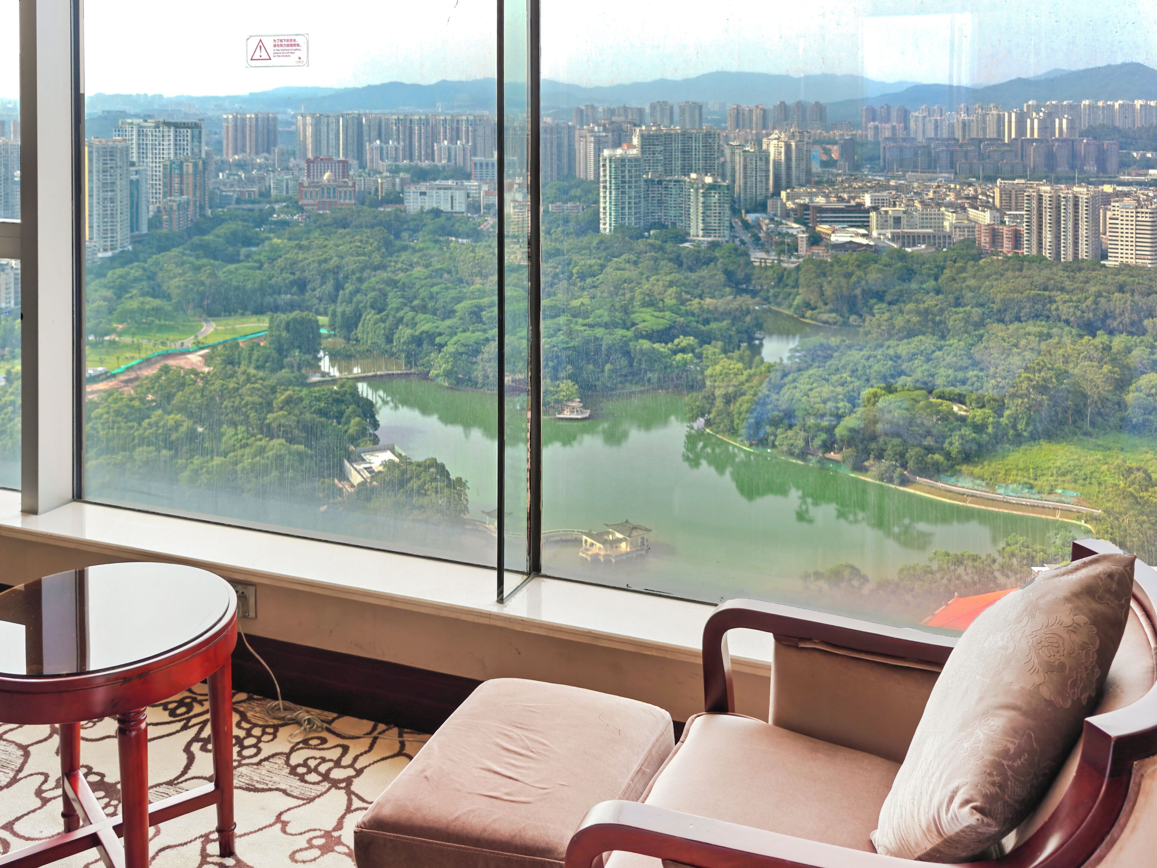 A hotel room with a large window offering a view of a cityscape and a river.