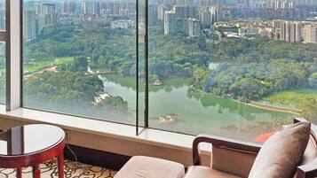 A hotel room with a large window offering a view of a cityscape and a river.