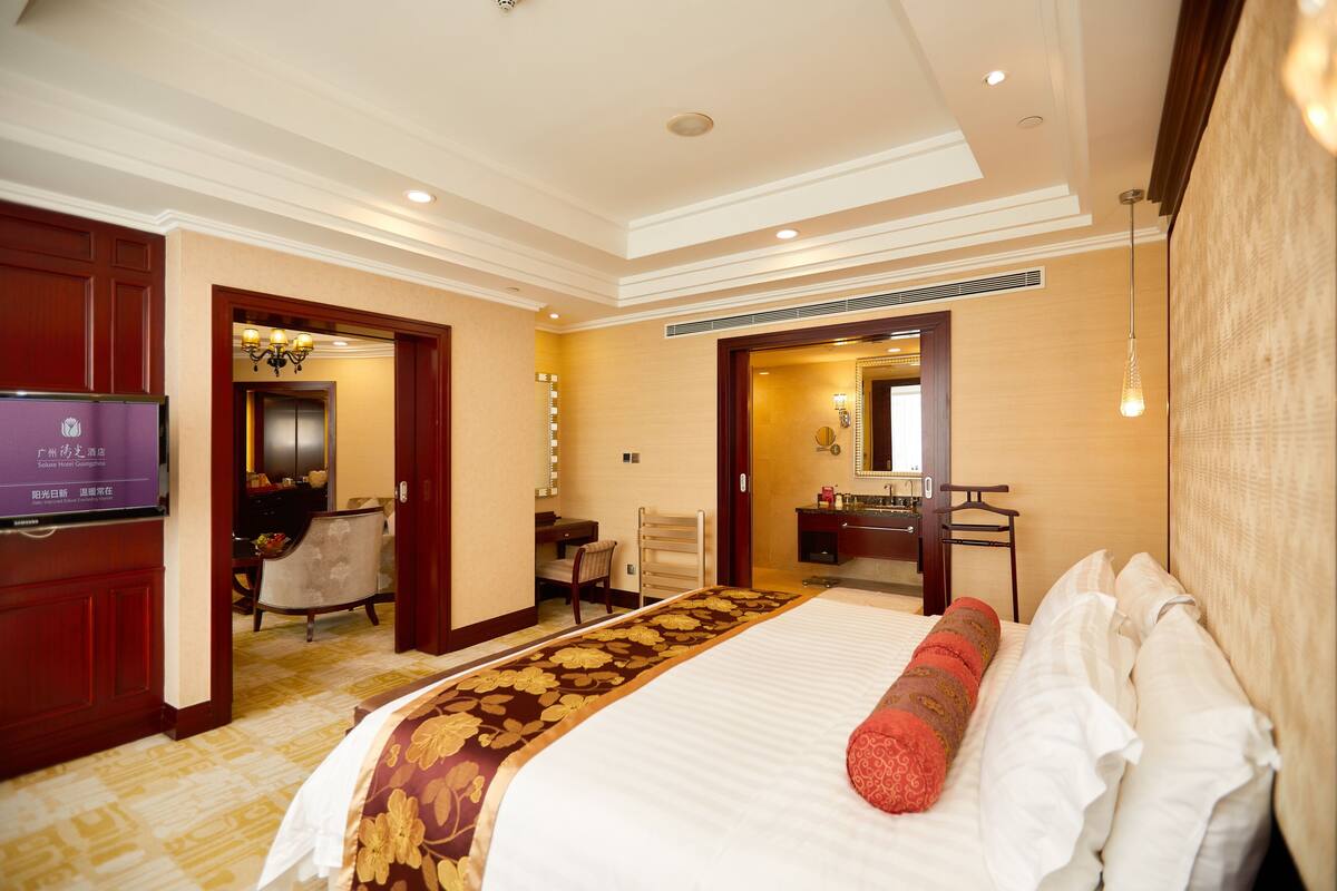 A hotel room with a large bed, a television, a desk, and a chair.